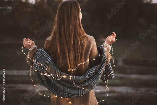 Portrait of girl with light LED garland outdoor holds a  lightes. Fairy illumination winter christmas mood. Selected focus photo