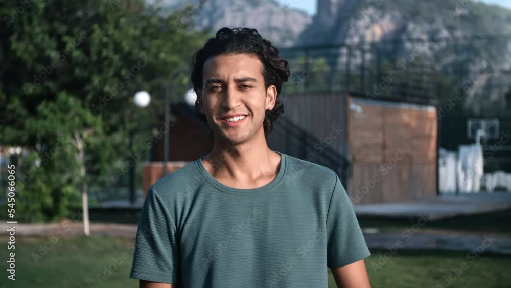 Portrait happy Latino young guy with curly hairs smiling posing summer mountain park landscape Portrait happy Latino young guy with curly hairs smiling posing summer mountain park landscape
