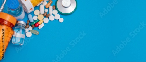 pills syringes stethoscope and test tubes on blue background abstract medical background photo