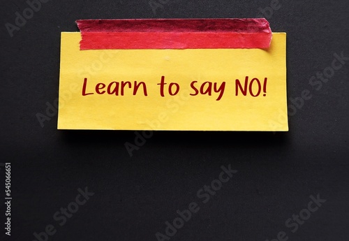 On black copy space background, yellow note stick with handwriting LEARN TO SAY NO, concept of people pleaser try not to feel guilty about saying no, no need to agree or say yes to everything photo