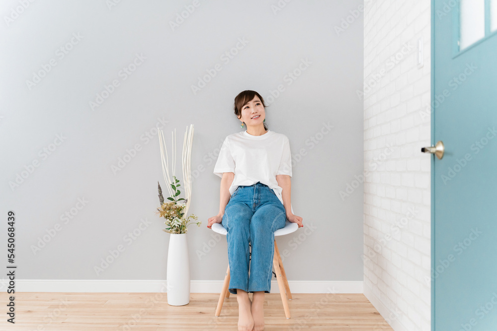 家で椅子に座るジーンズ姿のアジア人女性 Stock 写真 | Adobe Stock