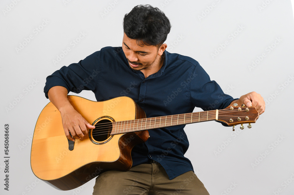 Portrait of Young Asian man playing an acoustic guitar isolated on white background