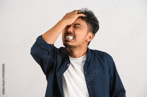 Portrait of Disappointed young asian man in blue shirt annoyed angry in furious gesture isolated on white background