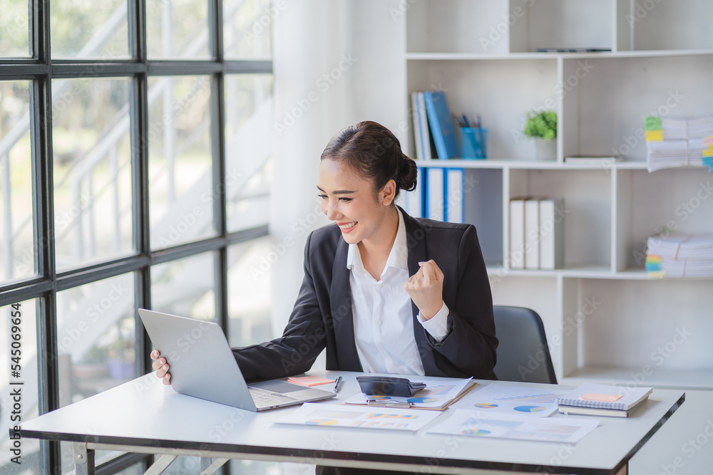 Beautiful Asian businesswoman celebrate while using laptop at office and showing delight. Startup small business and successful concept. Beautiful Asian businesswoman celebrate while using laptop at office and showing delight. Startup small business and successful concept.
