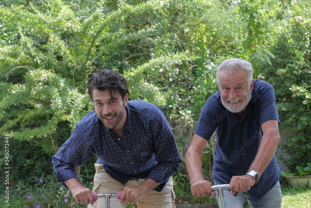 Fototapeta premium Happy old father and his son are playing scooters cheerfully together at outdoor garden house on holiday.