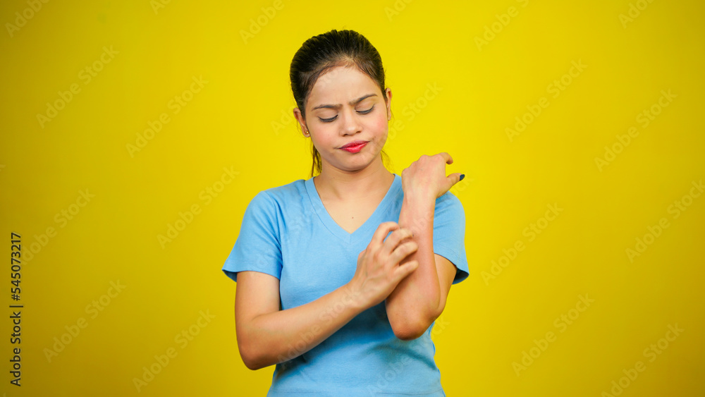 Young women have skin problems, irritation on her skin, skin infection itching red rash, arm scratching with hands, isolated over yellow background Young women have skin problems, irritation on her skin, skin infection itching red rash, arm scratching with hands, isolated over yellow background