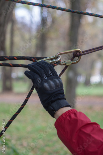 Hands of a climber and a rope close-up against the background of a green forest