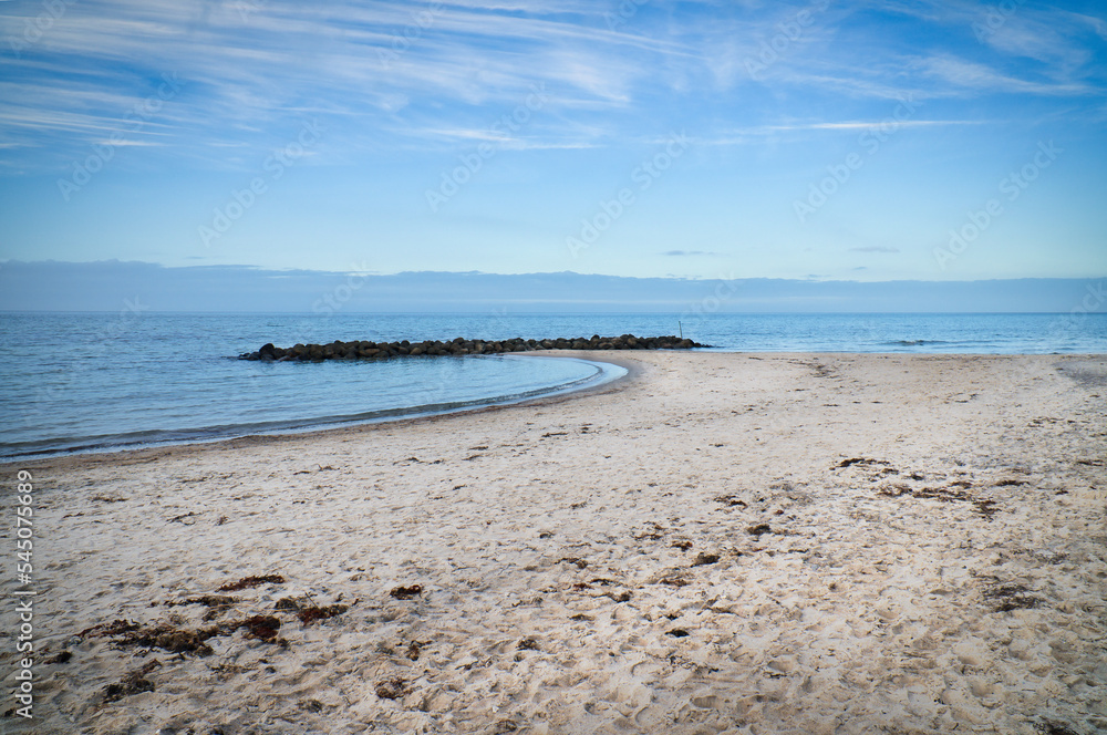 Sandy beach on the coast of Denmark. Stone groyne in the bay, sunshine while walking Sandy beach on the coast of Denmark. Stone groyne in the bay, sunshine while walking