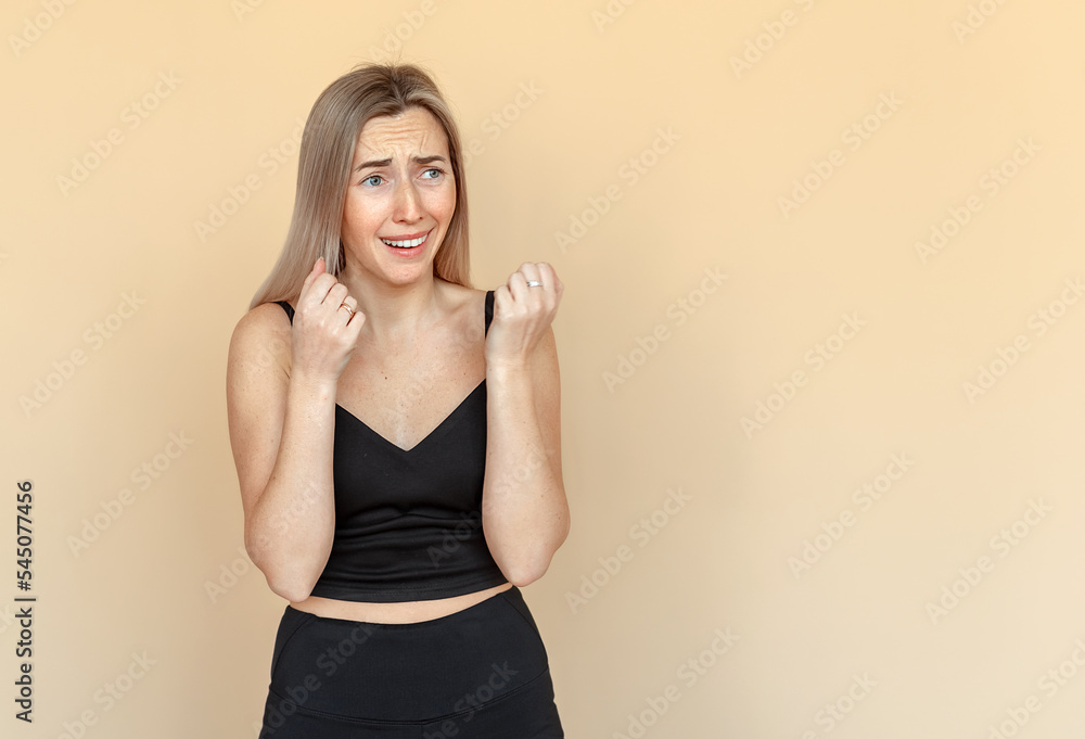 I'm afraid. Fright. Portrait of the scared young woman with freckles. Worried girl wearing casual black clothes standing over beige background with copy space I'm afraid. Fright. Portrait of the scared young woman with freckles. Worried girl wearing casual black clothes standing over beige background with copy space