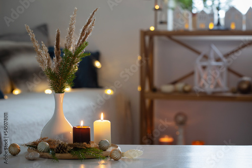 burning candles with christmas decor in white cozy interior