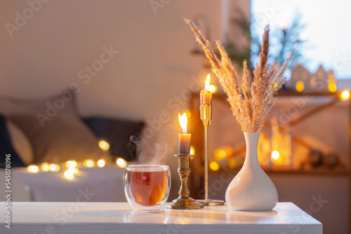 hot tea in thermo glass with christmas decor and burning candles at home