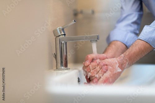 Man using soap and washing hands under the water tap. Hygiene concept hand closeup detail. 