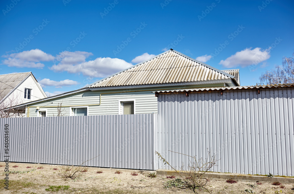 Fototapeta premium Facade of a European suburban building. Metal fence and house against a blue sky