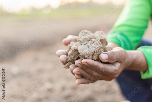 Hand holding dry soil at the field in sunrise or sunset time. Growth plant concept