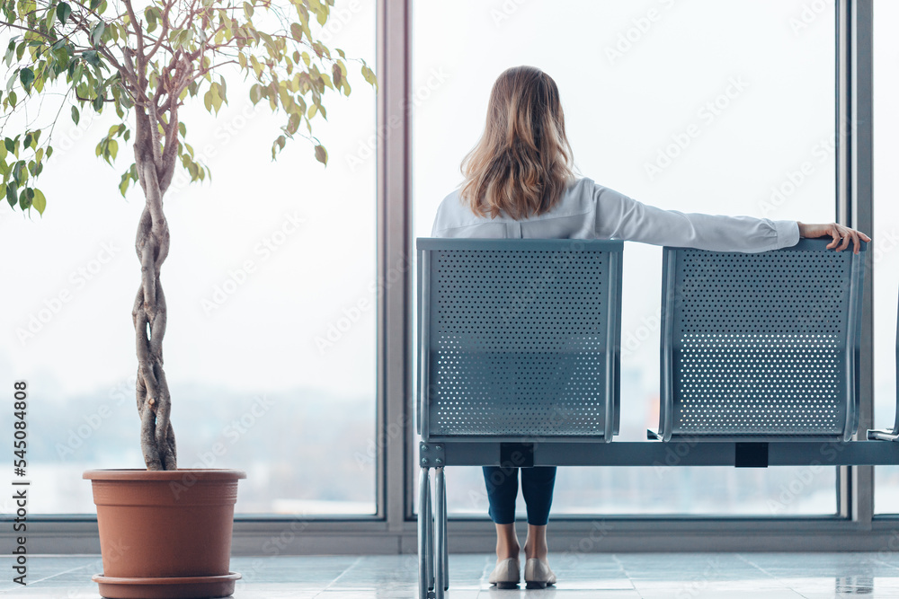 Young woman waiting for a flight in a modern airport lounge.