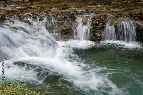 A waterfall in an autumn valley. Golden leaves and silky waters