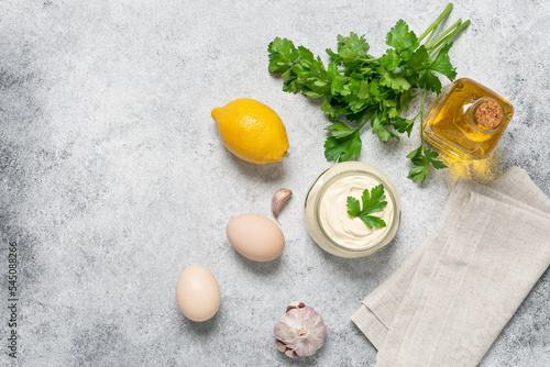 Aioli sauce with ingredients on a light rustic background. Homemade mayonnaise. View from above, copy space.