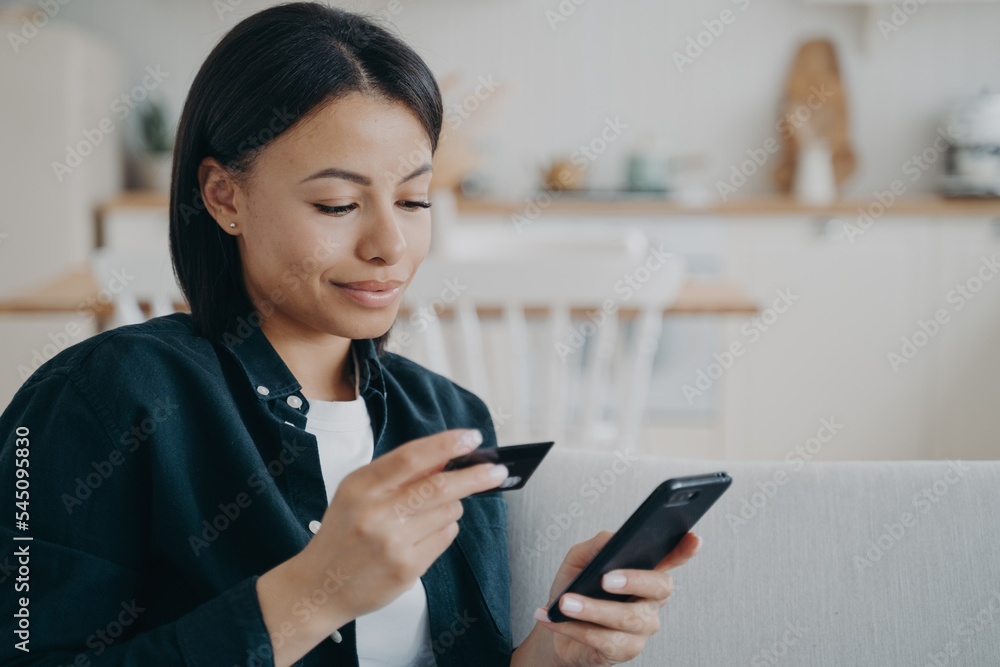 Female holding credit card, smartphone, using online banking services, mobile bank app at home Female holding credit card, smartphone, using online banking services, mobile bank app at home