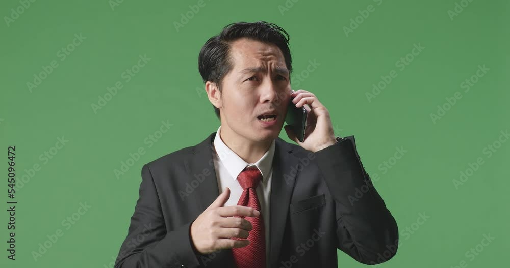 An Angry Asian Business Man Talking On Mobile Phone While Standing On Green Screen In The Studio
An Angry Asian Business Man Talking On Mobile Phone While Standing On Green Screen In The Studio
