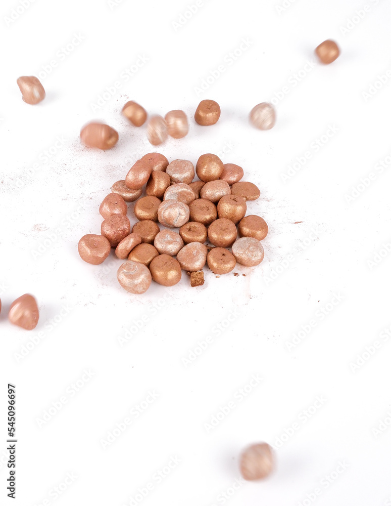 Balls of bronzing face powder falling on table, bronzing pearls isolated on white background Balls of bronzing face powder falling on table, bronzing pearls isolated on white background