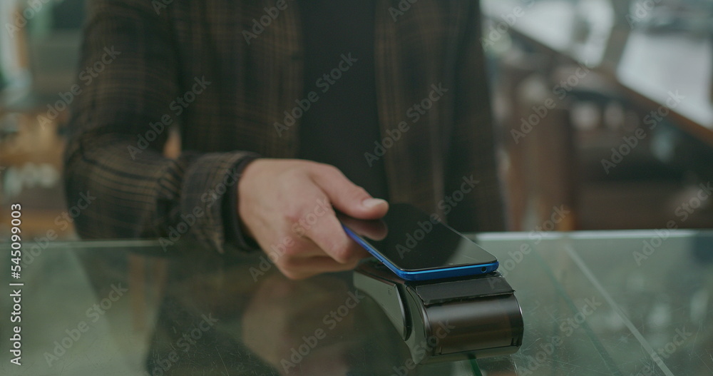 Young man customer paying order with cellphone wireless payment method. Male person using smartphone to pay product purchase Young man customer paying order with cellphone wireless payment method. Male person using smartphone to pay product purchase