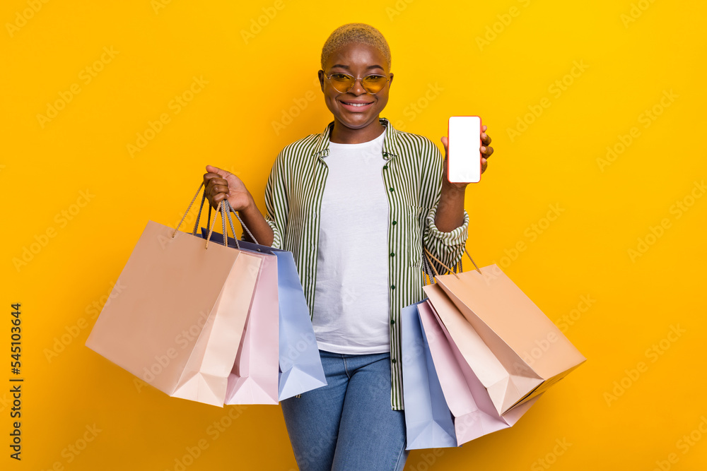 Portrait of positive pretty person hand hold packages demonstrate empty space display isolated on yellow color background Portrait of positive pretty person hand hold packages demonstrate empty space display isolated on yellow color background