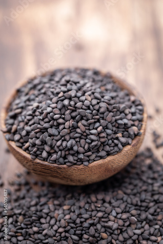 Bio natural black sesame seeds on wooden bowl.
