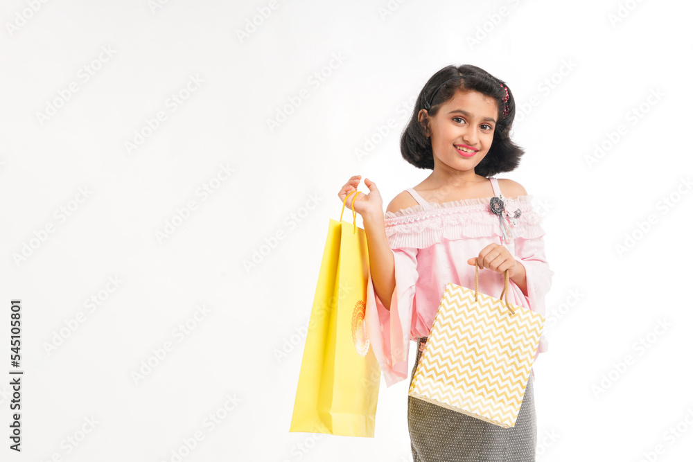 Happy Indian little girl holding shopping bags on white background. Happy Indian little girl holding shopping bags on white background.