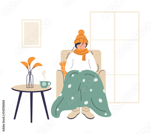 Young woman wrapped in plaid. Frozen female character in hat and scarf. Low temperature at home. Person freezes from cold warming up with hot drink. Girl sitting in armchair, shivering from cold.