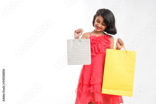 Happy Indian little girl holding shopping bags on white background.