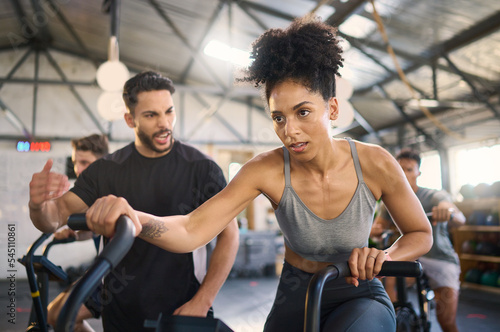 Exercise bike, motivation and personal trainer with a black woman in gym for exercise or fitness. Wellness, training and cycling with a female and coach working together in a health or wellness club