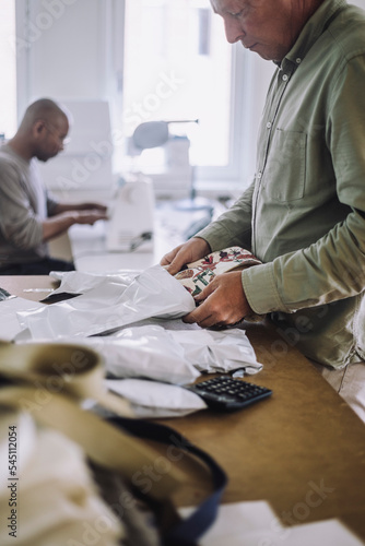 Male fashion designer packing fabric while working at workshop