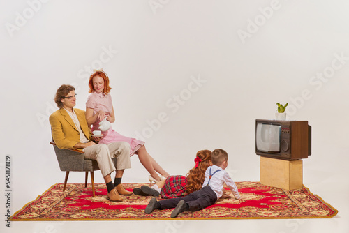 Portrait of young family watching TV isolated over grey background photo