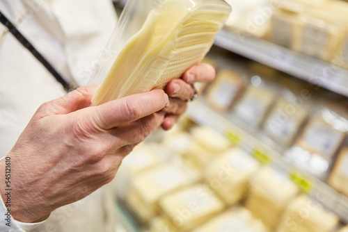 Kunde hält Käse Packung und liest Produkt Information photo