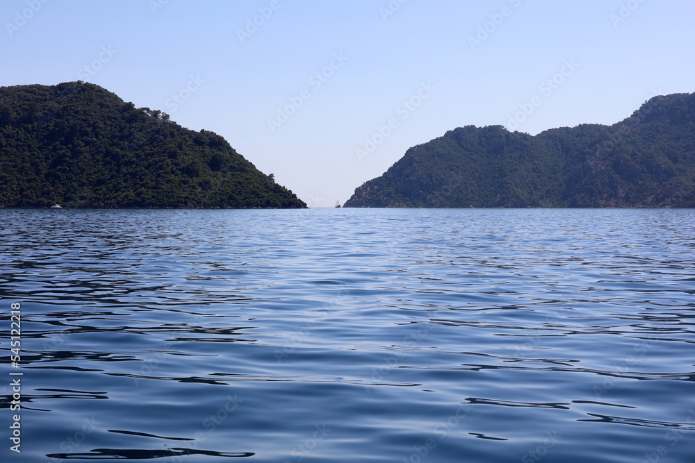 View to blue sea and strait between the mountain islands on horizon. Deep water surface, background for traveling and vacation