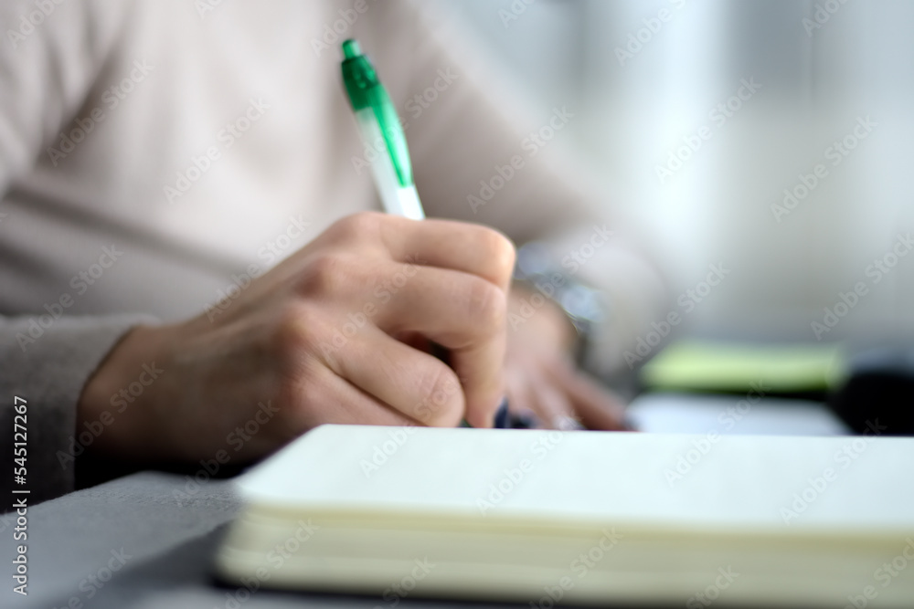 Fototapeta premium woman's hand writing in a diary using a ballpoint pen. selective focus