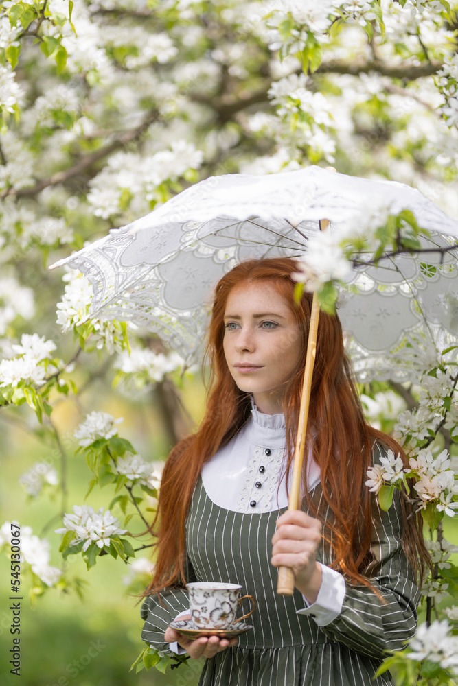 Fototapeta premium Girl with a lace umbrella in the spring garden