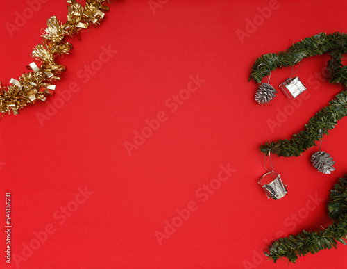 Christmas decoration. Golden and green tinsels with some silver decoration. Red background