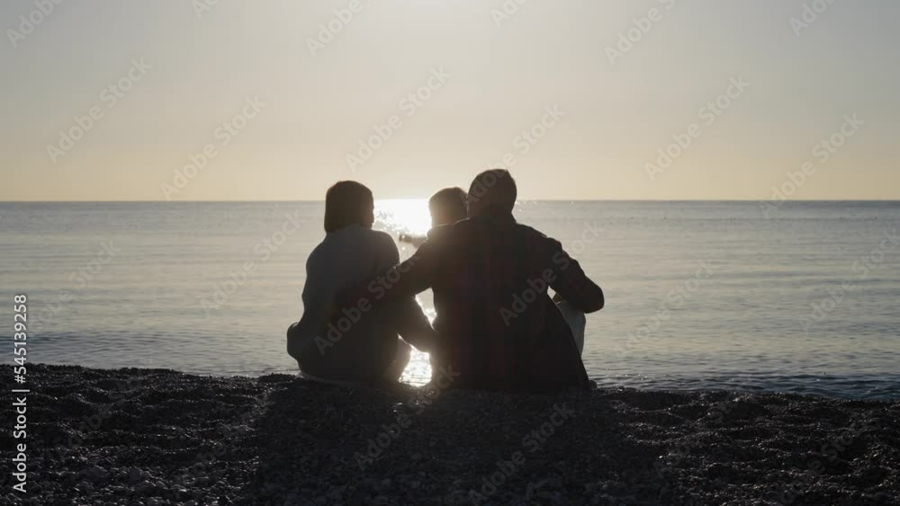 Happy young family walking on the beach into the sunset. High quality 4k footage Happy young family walking on the beach into the sunset. High quality 4k footage