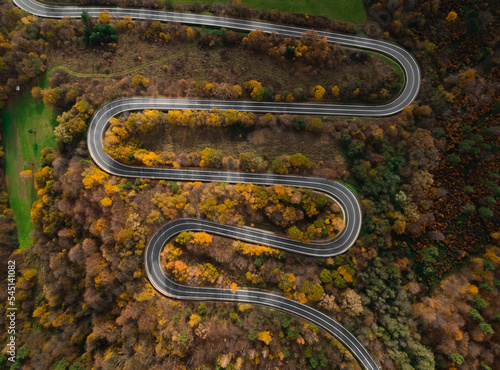 Fototapeta Naklejka Na Ścianę i Meble -  Autumn winding road in a mountain surounded by an autumn forest in Europe.