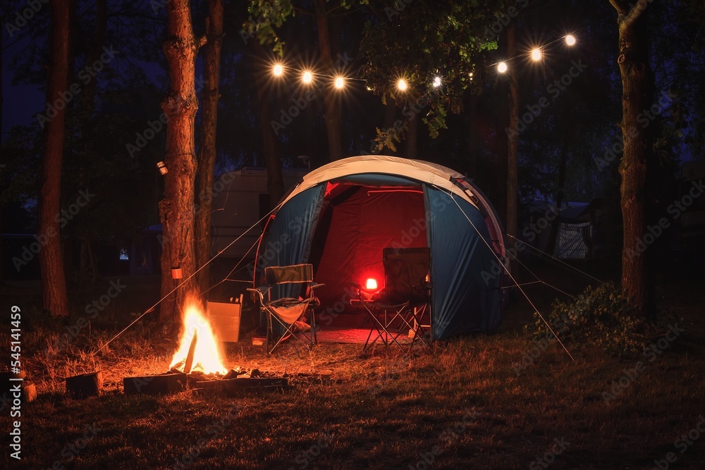 Atmospheric night adventure. Tent with a midnight fire in the forest.