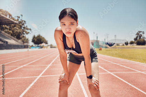 Sports, stadium and runner woman in portrait for fitness, training and competition with blue sky mock up. Young athlete girl with exercise, wellness and goals for marathon or a race track event © L Ismail/peopleimages.com