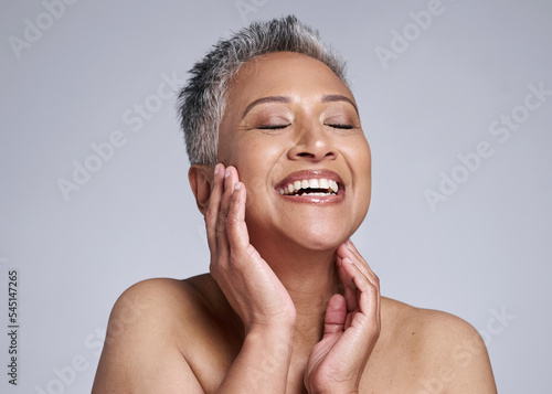 Beauty, face and happy mature woman, glowing skincare and dermatology of anti aging cosmetics on grey studio background. Smile, joy and wellness of lady model with confidence, happiness and self care photo