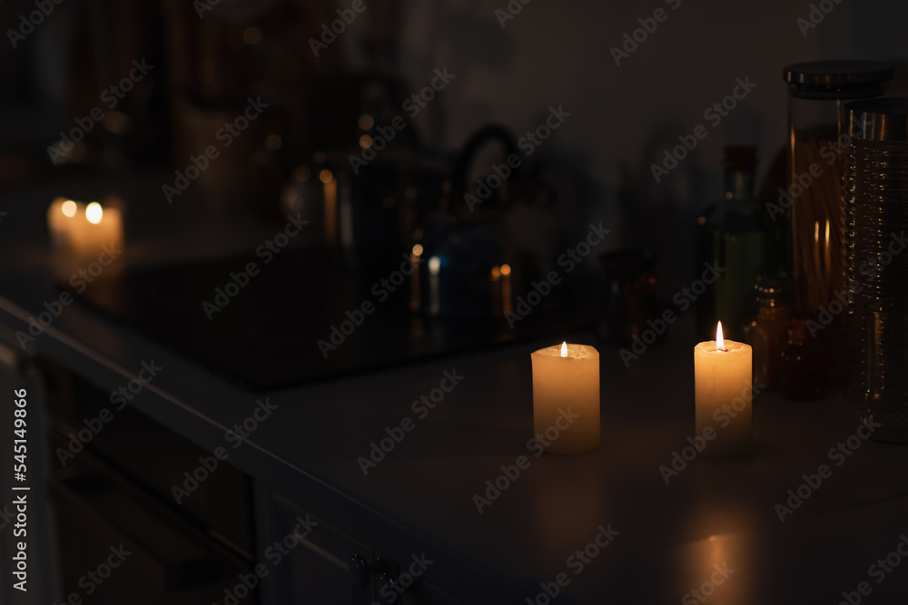 kitchen counter with kitchenware and lit candles during energy blackout. kitchen counter with kitchenware and lit candles during energy blackout.
