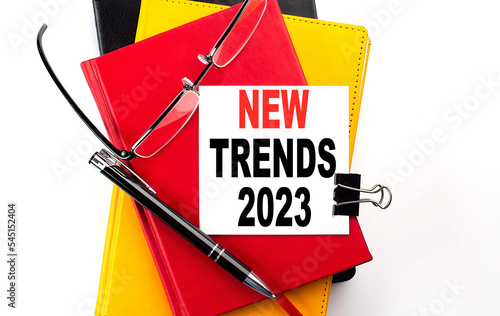 NEW TRENDS 2023 text written on a sticky on colorful notebooks photo