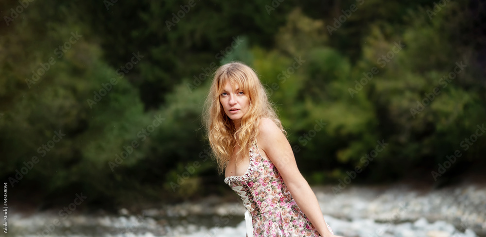 wide panorama banner portrait of beautiful sexy blond young woman in dirndl fashion standing in austrian pebble riverbed wide panorama banner portrait of beautiful sexy blond young woman in dirndl fashion standing in austrian pebble riverbed
