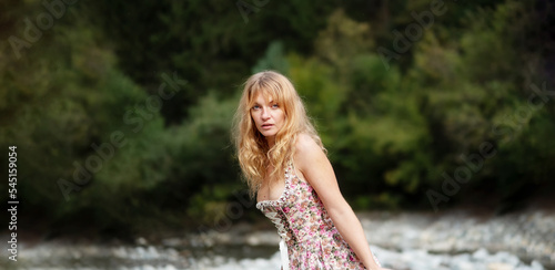 wide panorama banner portrait of beautiful sexy blond young woman in dirndl fashion standing in austrian pebble riverbed