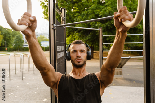 Young man listening to music with headphones during workout in park