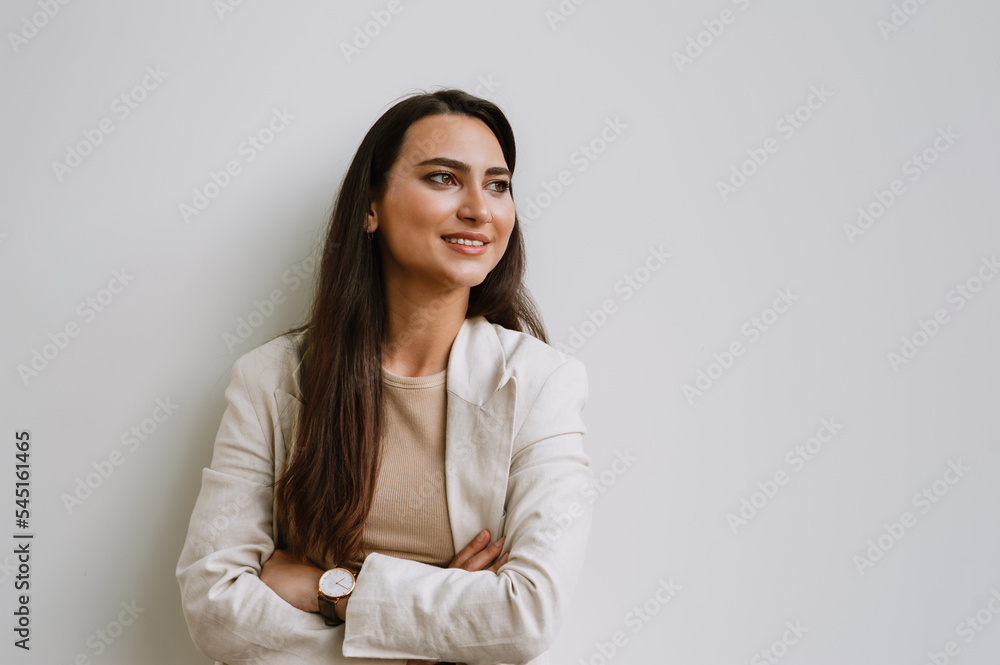 Young indian woman smiling and looking aside while standing by wall Young indian woman smiling and looking aside while standing by wall