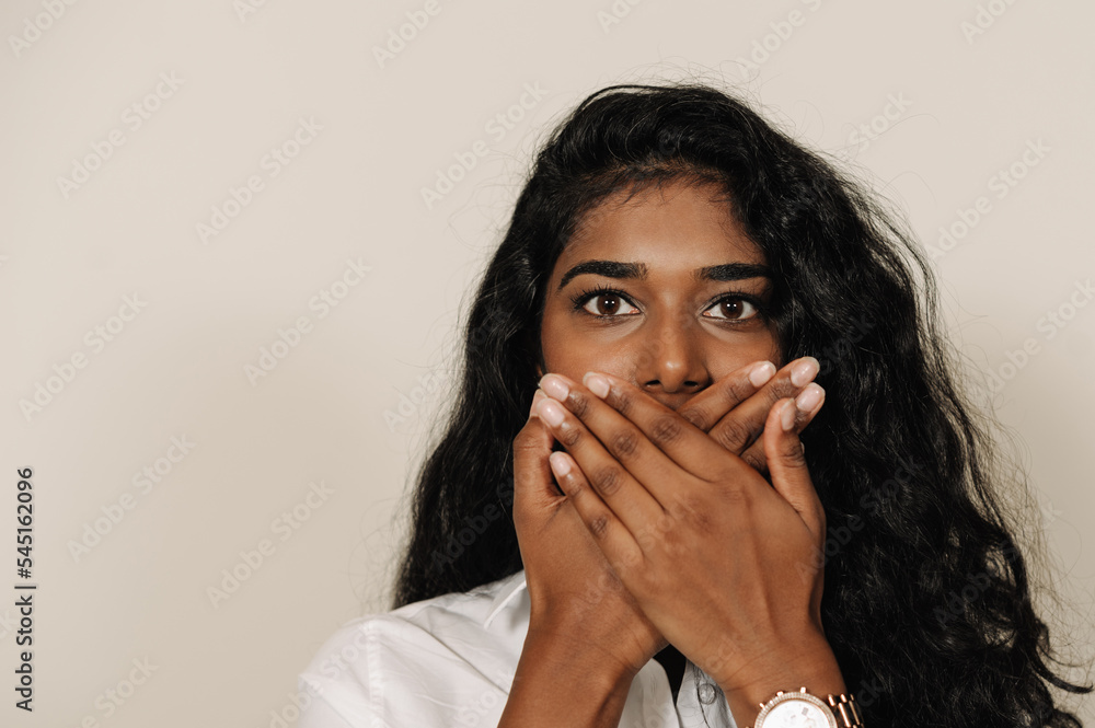 Young brunette indian woman covering her mouth and expressing surprise Young brunette indian woman covering her mouth and expressing surprise